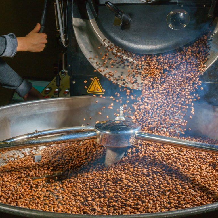 Grains de café torréfiées tombant dans un récipient lors du processus de torréfaction.