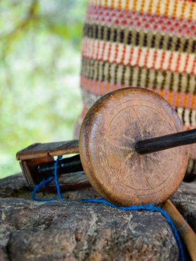 Un objet en bois avec un manche, posé sur une pierre, entouré de tissu coloré.