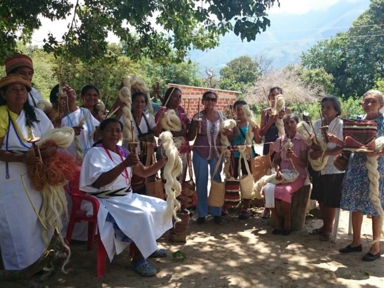 Groupe de femmes en vêtements traditionnels avec des paniers et des tresses, en plein air.